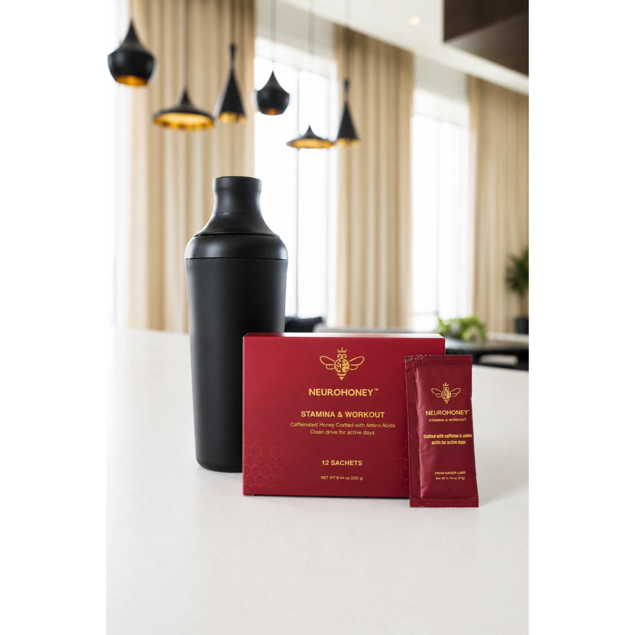 A black shaker bottle, a red box of Neuronhoney Stamina & Workout powder, and a single red sachet packet on a white countertop in a modern kitchen setting.